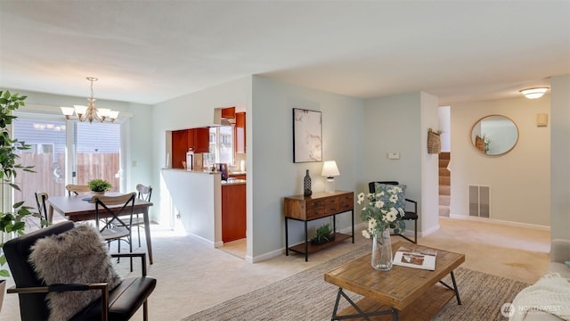 living area featuring light colored carpet, a healthy amount of sunlight, visible vents, and an inviting chandelier