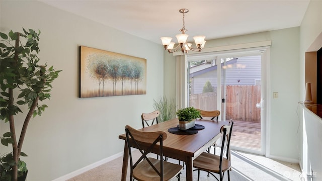 carpeted dining area featuring a notable chandelier and baseboards