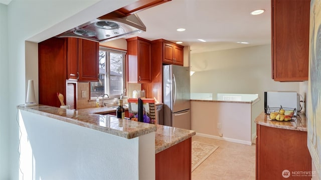 kitchen featuring recessed lighting, a peninsula, baseboards, freestanding refrigerator, and tasteful backsplash