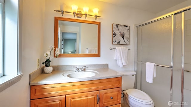 bathroom featuring toilet, a shower stall, and vanity