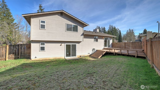 rear view of property with a fenced backyard, a yard, a chimney, and a wooden deck