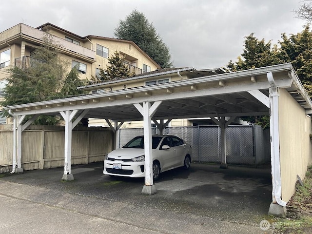 view of vehicle parking with fence and a carport