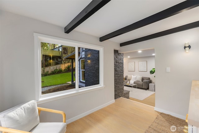 living area featuring baseboards, wood finished floors, and beamed ceiling