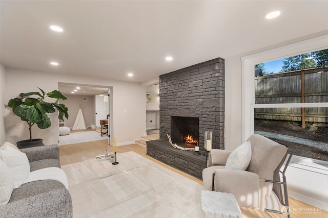 living room with recessed lighting, a stone fireplace, baseboards, and wood finished floors