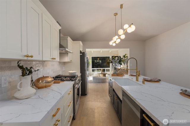 kitchen featuring white cabinets, light wood-style flooring, appliances with stainless steel finishes, pendant lighting, and a sink