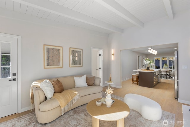 living room featuring light wood-style floors, beam ceiling, a chandelier, and baseboards