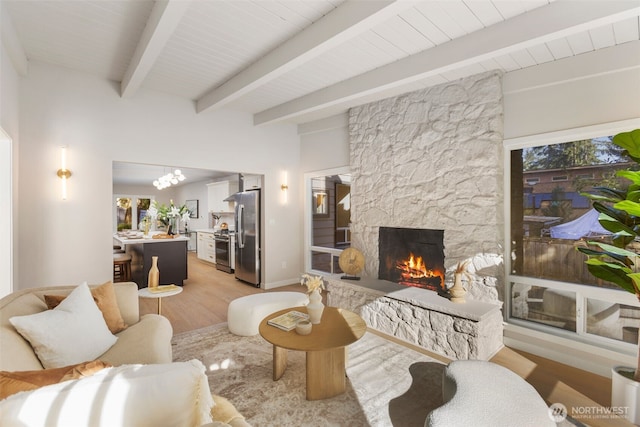 living room featuring light wood-type flooring, a fireplace, and beam ceiling