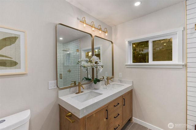 bathroom with a healthy amount of sunlight, tiled shower, a sink, and toilet