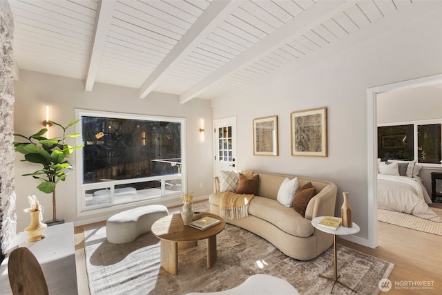 living room with lofted ceiling with beams, wood finished floors, and baseboards