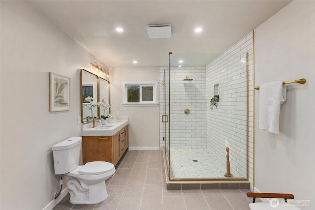 bathroom featuring tile patterned flooring, toilet, vanity, baseboards, and a stall shower