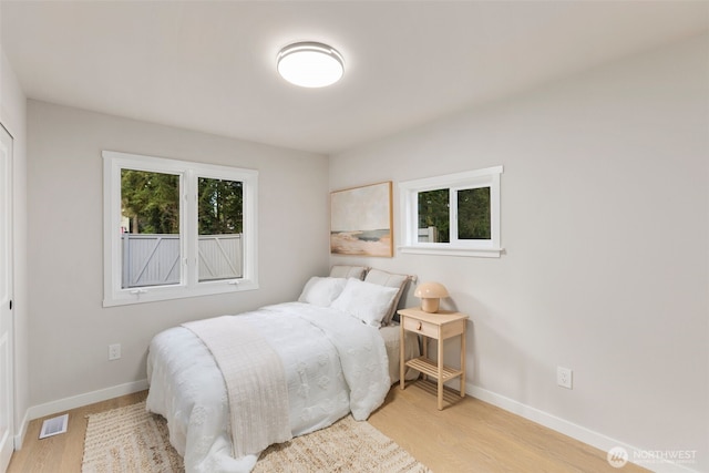 bedroom with light wood finished floors, baseboards, and visible vents