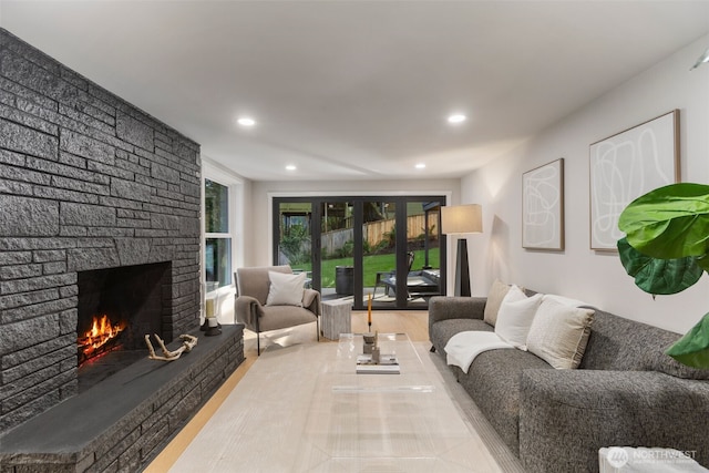 living area featuring recessed lighting, wood finished floors, and a stone fireplace