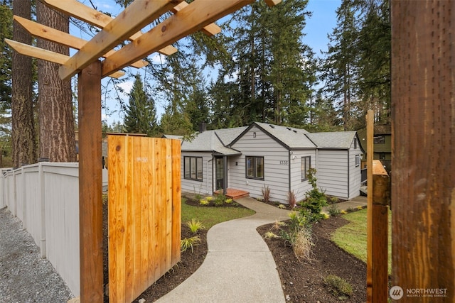 view of front of property featuring fence and a pergola