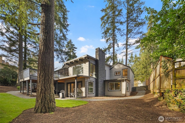 rear view of house featuring a lawn, a patio, a chimney, a wooden deck, and central air condition unit