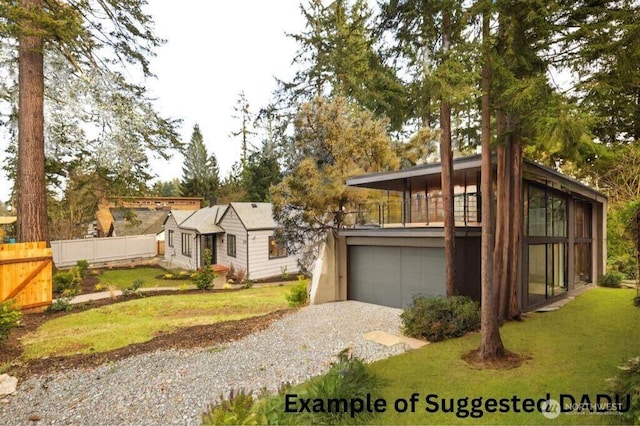 view of front of house featuring a garage, driveway, a front lawn, and fence