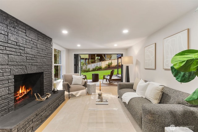 living room featuring a stone fireplace, wood finished floors, and recessed lighting