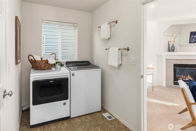 washroom with laundry area, baseboards, visible vents, a tile fireplace, and independent washer and dryer