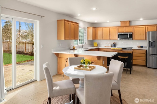 kitchen featuring stainless steel appliances, a sink, light countertops, and recessed lighting