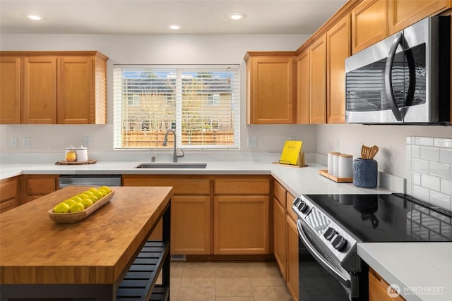 kitchen with stainless steel appliances, a sink, wooden counters, and recessed lighting