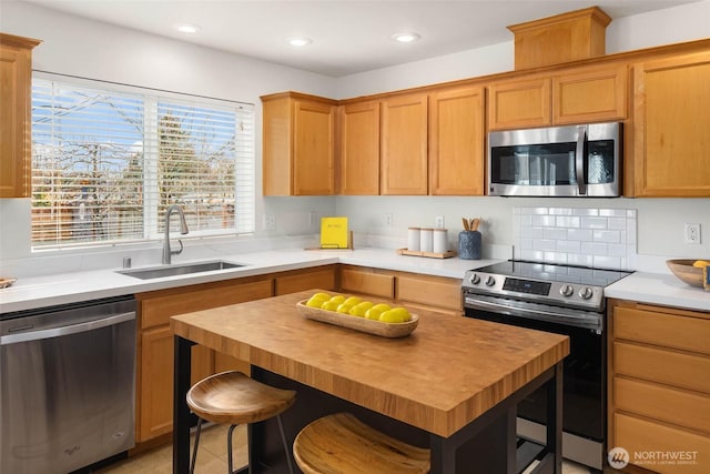 kitchen featuring butcher block counters, appliances with stainless steel finishes, a kitchen breakfast bar, a sink, and recessed lighting