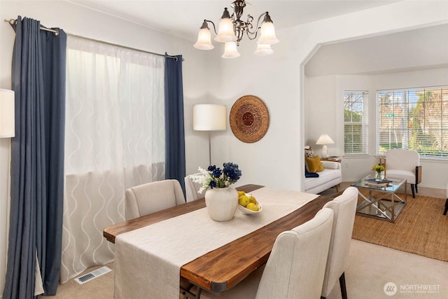 dining area featuring carpet, visible vents, and a chandelier