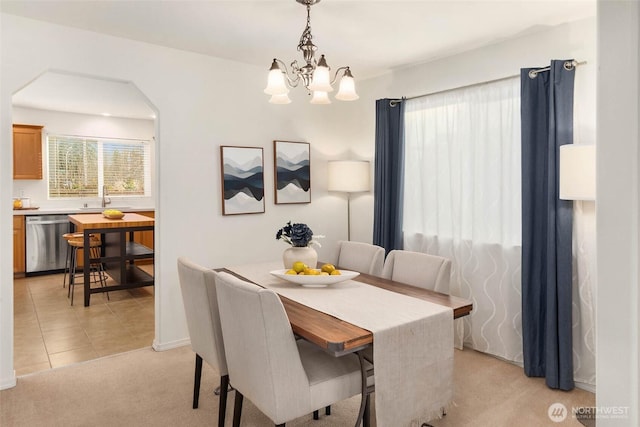 dining area with arched walkways, light tile patterned flooring, a notable chandelier, light carpet, and baseboards