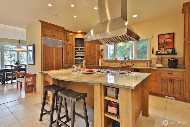 kitchen with island exhaust hood, open shelves, a sink, stainless steel gas stovetop, and brown cabinetry