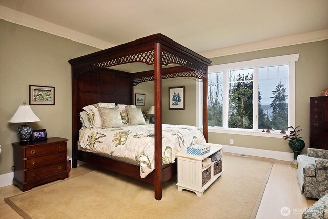 bedroom featuring wood finished floors, visible vents, baseboards, and ornamental molding