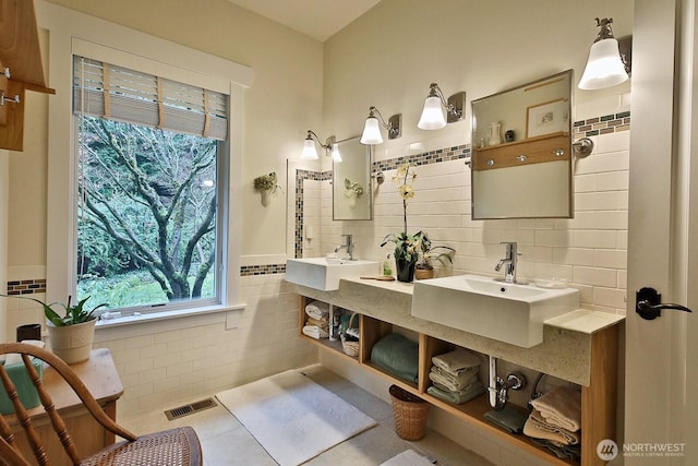 full bath with a sink, visible vents, tile walls, and tile patterned flooring