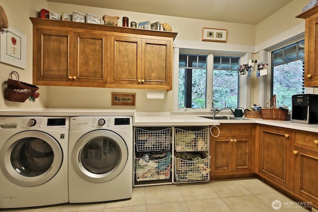 washroom featuring light tile patterned floors, washing machine and dryer, cabinet space, and a sink