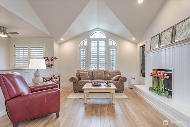 living room featuring lofted ceiling, light wood finished floors, baseboards, and a wealth of natural light