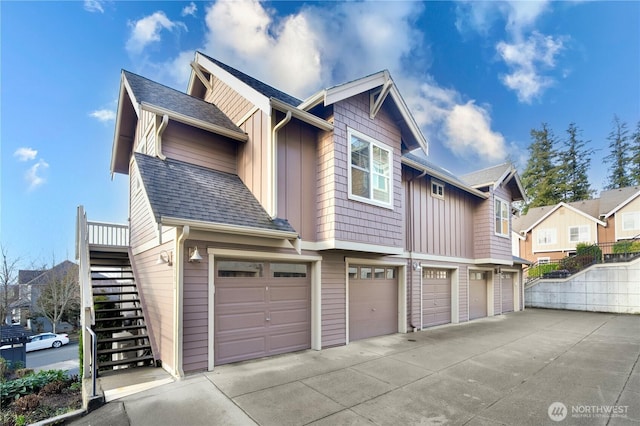 view of side of property with a garage, roof with shingles, stairway, and board and batten siding