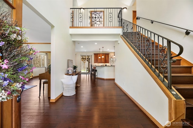 foyer entrance featuring wood-type flooring, baseboards, stairway, and a high ceiling