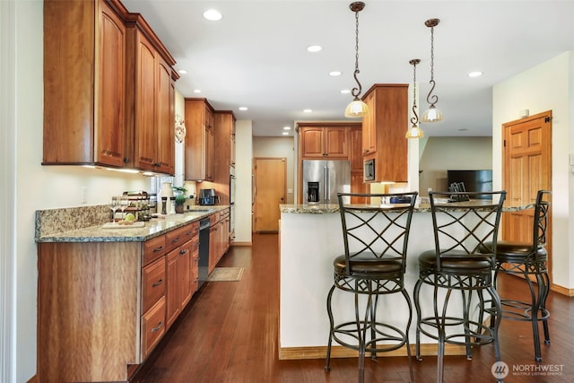 kitchen featuring stainless steel appliances, dark wood-type flooring, light stone countertops, and a kitchen breakfast bar