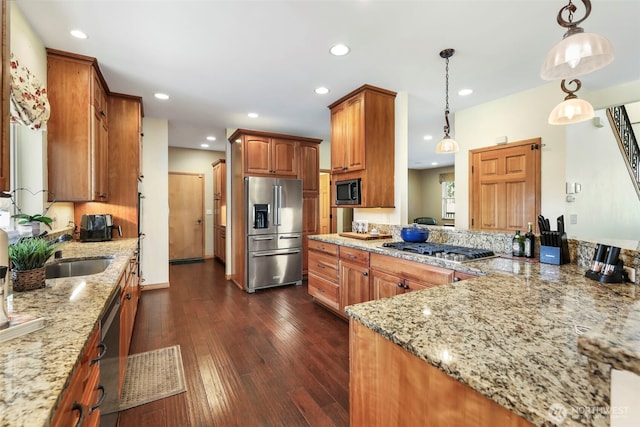 kitchen with appliances with stainless steel finishes, dark wood-type flooring, light stone countertops, a sink, and recessed lighting