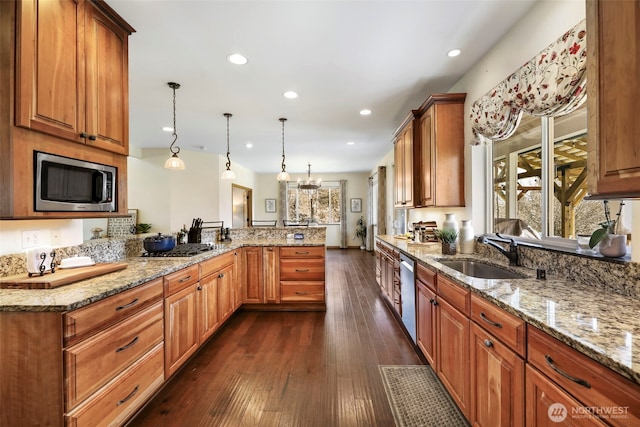 kitchen featuring stainless steel appliances, recessed lighting, dark wood-type flooring, a sink, and a peninsula