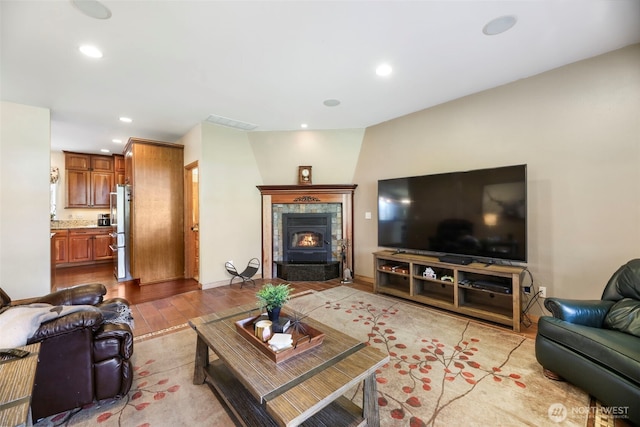 living area with a fireplace, light wood finished floors, recessed lighting, visible vents, and baseboards