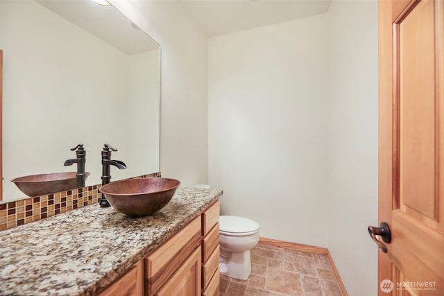 bathroom with tasteful backsplash, vanity, toilet, and baseboards