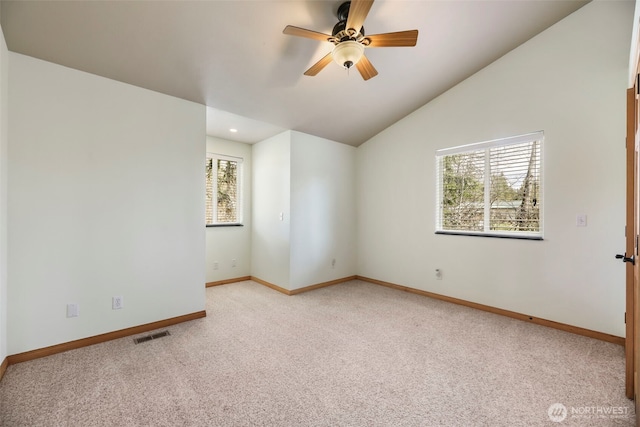 empty room featuring lofted ceiling, visible vents, a ceiling fan, baseboards, and carpet