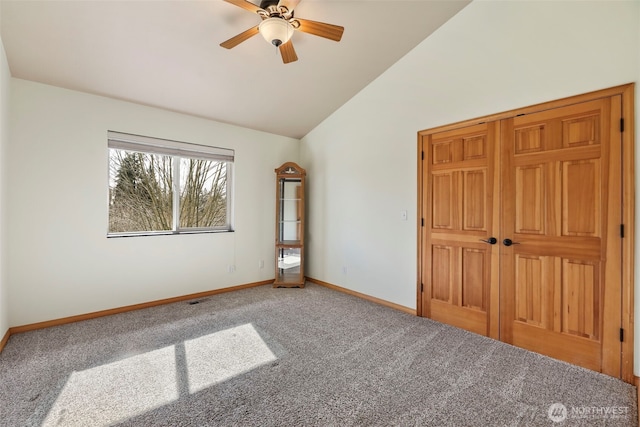 unfurnished bedroom featuring carpet floors, baseboards, vaulted ceiling, and a ceiling fan