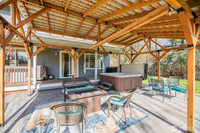 wooden terrace featuring a gazebo, a patio area, a hot tub, and outdoor dining space