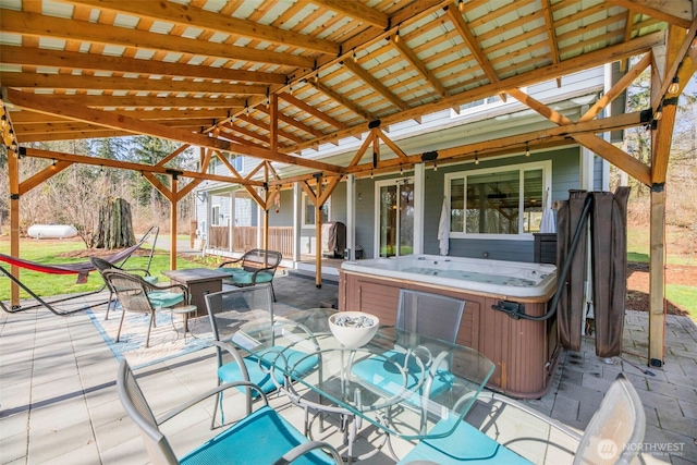 view of patio with a fire pit, outdoor dining area, and a hot tub