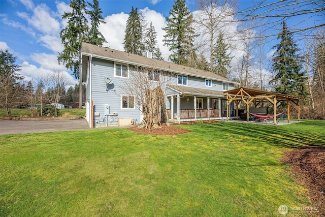 back of property with a yard and a gazebo