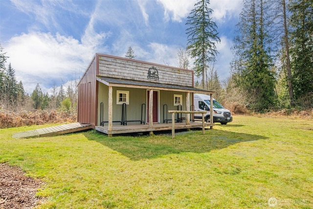 rear view of property featuring a yard and an outdoor structure