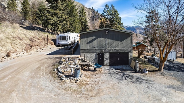 view of front of property featuring dirt driveway and an outdoor structure