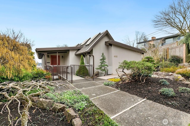 mid-century modern home featuring fence and stucco siding