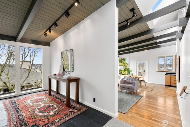 interior space with rail lighting, a healthy amount of sunlight, wooden ceiling, and vaulted ceiling with beams