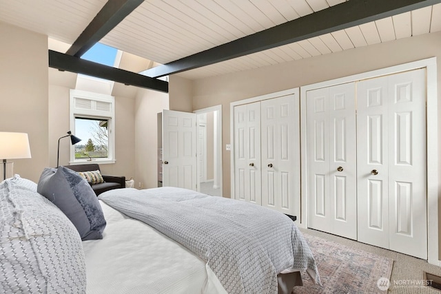 bedroom featuring multiple closets, light colored carpet, and vaulted ceiling with beams