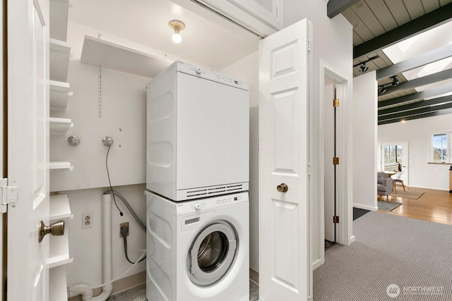 laundry room featuring stacked washer / drying machine, carpet floors, and laundry area