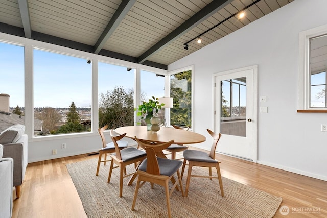 dining room with lofted ceiling with beams, baseboards, light wood-style floors, and a healthy amount of sunlight